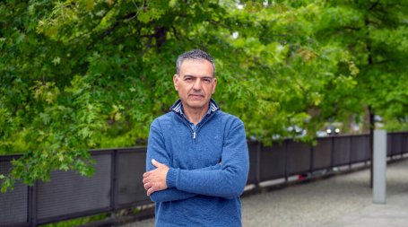 homem meia idade no jardim de braços cruzados a olhar de frente para a câmara