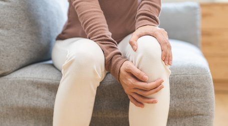Pessoa agarrada à perna com dores de joelho