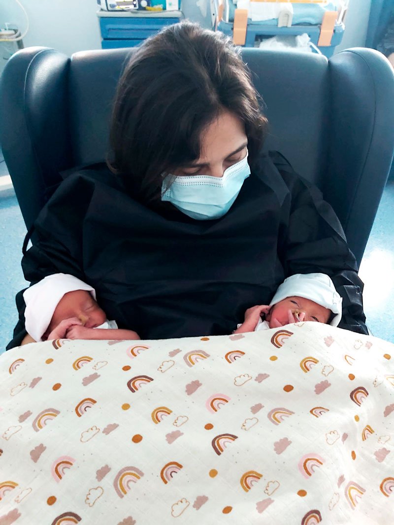 jovem mãe com filhas gémeas prematuras ao colo