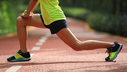 Mulher atleta faz alongamentos antes de começar a correr