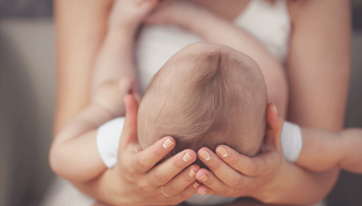 Mãe segura em cabeça de bebé com microcefalia