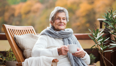 Mulher idosa agasalhada ingere bebida quente para se proteger do frio