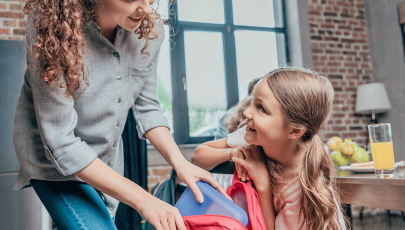 Mãe ajuda filha a preparar lancheira no regresso às aulas