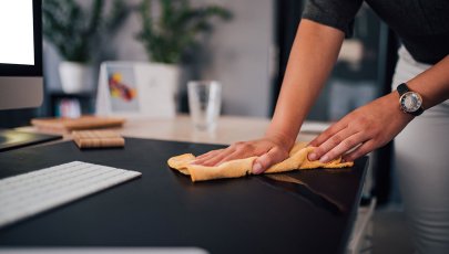 Mulher desinfecta secretária do trabalho para prevenir infeção por COVID-19