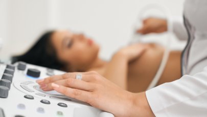 Médica realiza ecografia a mulher para vigilância de fibroadenoma e quisto da mama