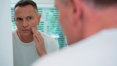 Homem avalia cara ao espelho, procura sinais de paralisia facial