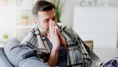 Homem assoa-se devido a sintomas de gripes e constipações