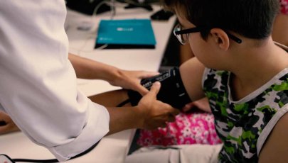 imagem de uma criança numa consulta com uma médica a medir a sua tensão.