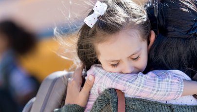 Criança com ansiedade de separação abraça mãe.