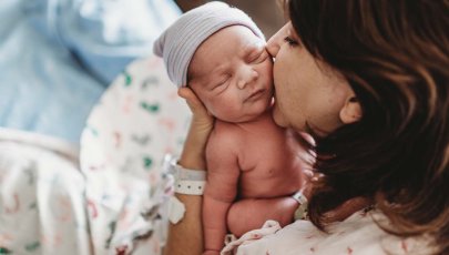 Mãe beija bebé recém-nascido na maternidade