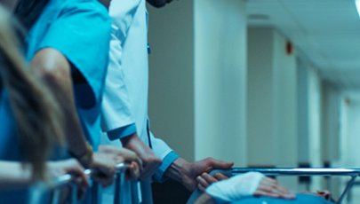 Um médico e duas enfermeiras dão assistência a um paciente deitado numa maca.