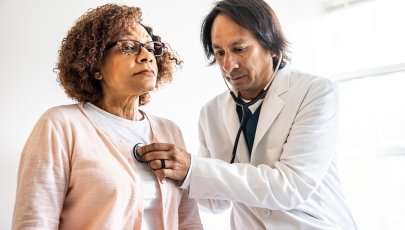 Mulher é auscultada por médico.