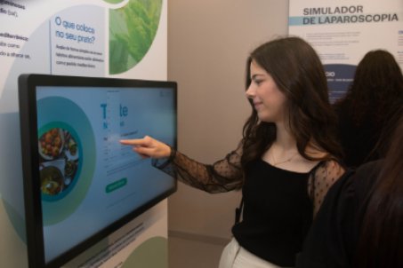 mulher jovem a experimentar ecrã da exposição dos 80 anos da CUF