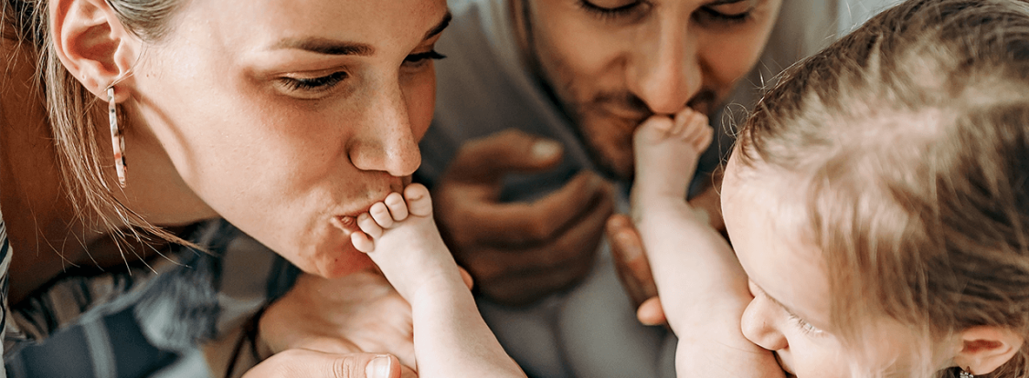 mãe e pai a beijar pés do bebé