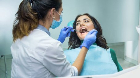 Médica dentista, em consulta, faz avaliação para despistar cancro oral na paciente