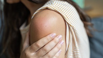 Mulher com dor no ombro após toma de vacina